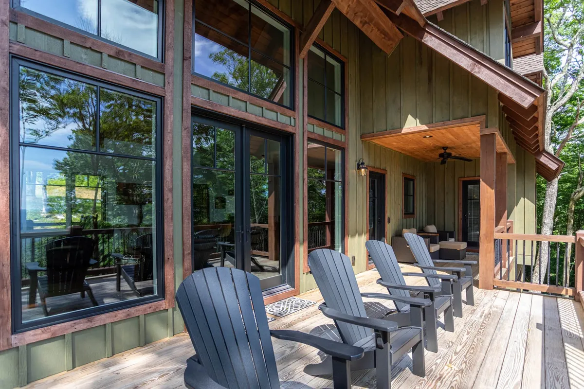 An inviting exterior deck with Adirondack chairs, large windows, and natural surroundings. The area looks perfect for relaxing, socializing, or simply taking in sunset views and crisp mountain air.