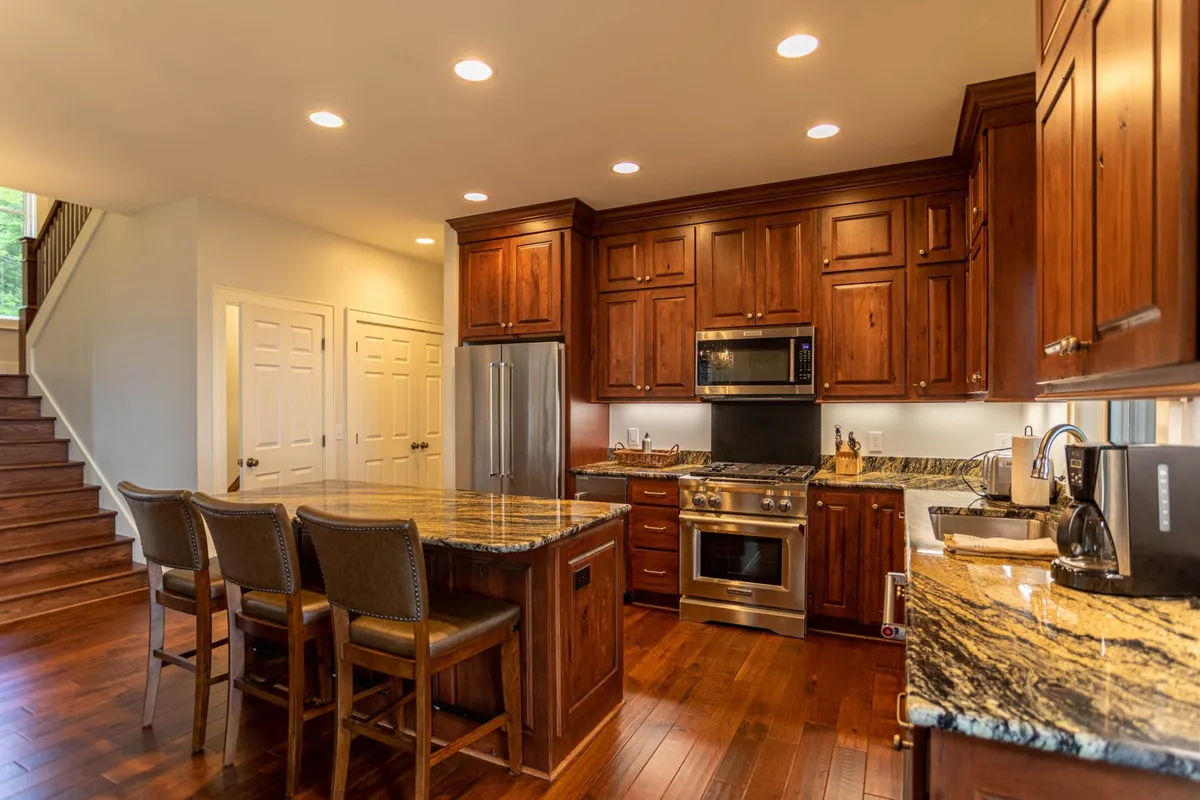 A cozy, functional kitchen scene with a spacious island, sleek stainless steel appliances, and warm wood cabinetry. The layout is open and encourages both cooking and socializing, emphasizing the kitchen's role in family gatherings and entertaining.